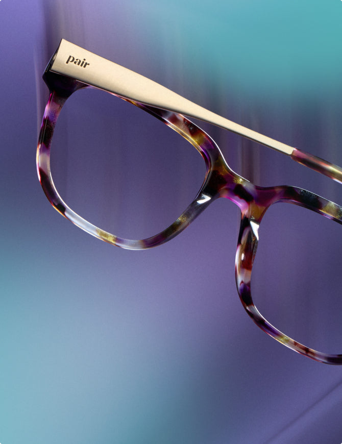 Pair eyeglasses with a gold bridge on a gradient blue background
